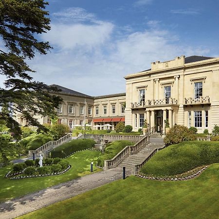 Macdonald Bath Spa Hotel Eksteriør bilde The photo shows a grand building, likely a hotel or estate, surrounded by well-manicured gardens and lawns. The architecture appears elegant, with multiple stories and large windows. There are steps leading up to the entrance, and the setting include