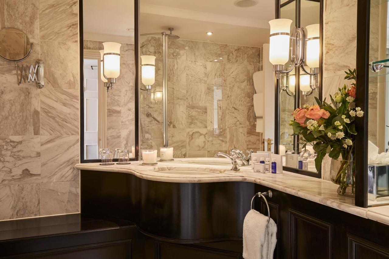 Macdonald Bath Spa Hotel Eksteriør bilde The photo shows a luxurious bathroom featuring elegant design elements. There is a curved marble countertop with a sink, complemented by stylish silver fixtures. The walls are adorned with light-colored marble, creating a sophisticated ambiance. Seve