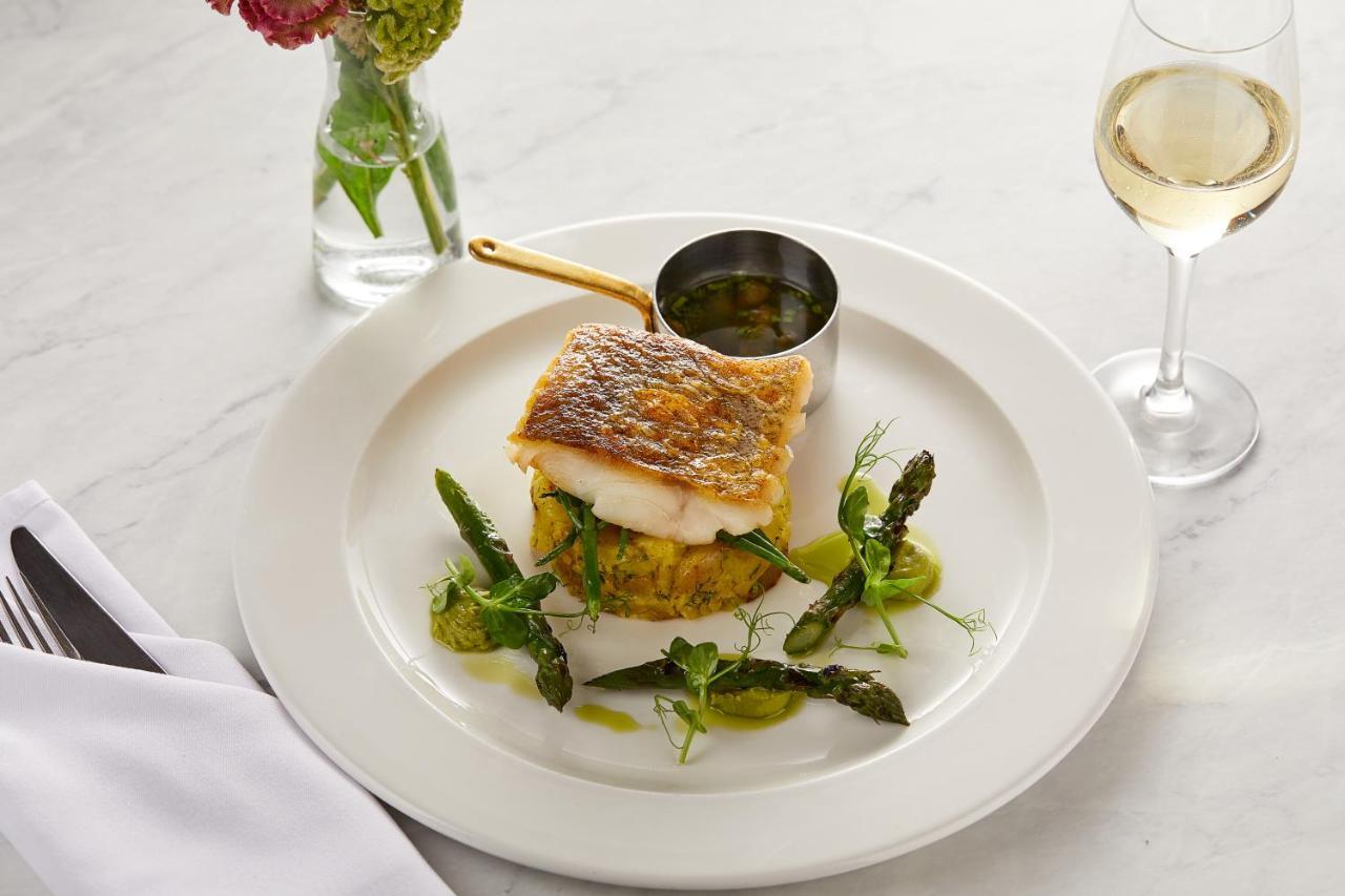 Macdonald Bath Spa Hotel Eksteriør bilde The photo showcases a beautifully plated dish featuring a piece of fish, likely with a crispy skin, resting on a bed of what appears to be a savory cake or puree. Surrounding the fish are fresh asparagus and garnishes, adding a touch of color and fre