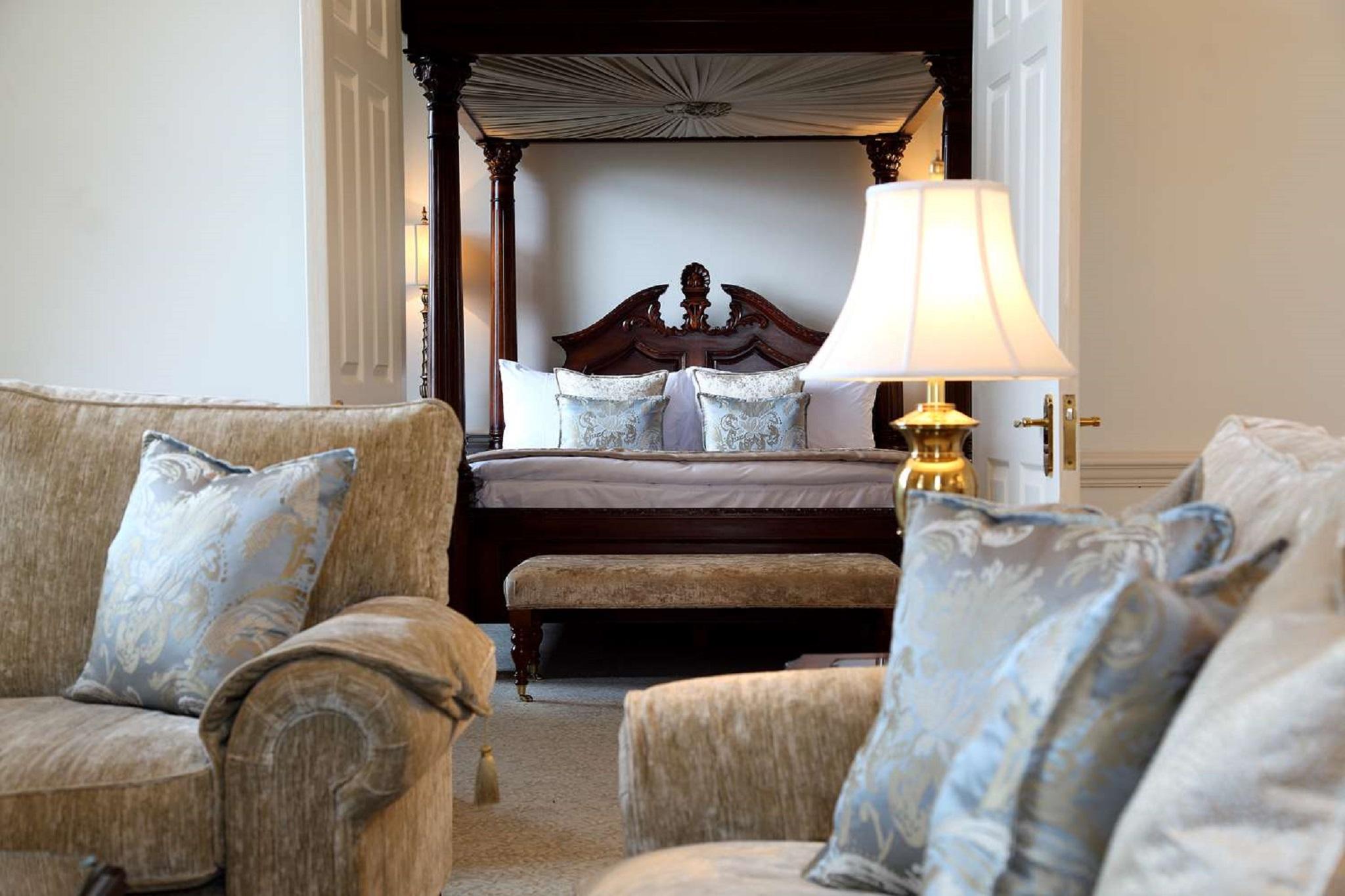 Macdonald Bath Spa Hotel Eksteriør bilde The photo shows a beautifully decorated room featuring a four-poster bed in the background. The bed has a wooden frame with a rich design, and it is adorned with plush bedding and pillows. In the foreground, there are comfortable sofas with decorativ