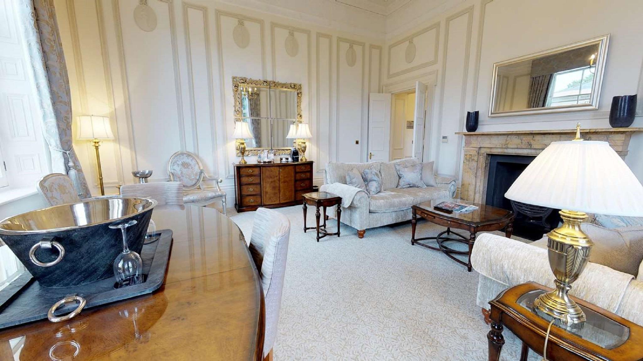Macdonald Bath Spa Hotel Eksteriør bilde The photo depicts a elegantly furnished living room. It features light-colored walls with subtle decorative details and a plush carpet. In the room, there are several pieces of furniture, including a pair of sofas and armchairs arranged around a smal