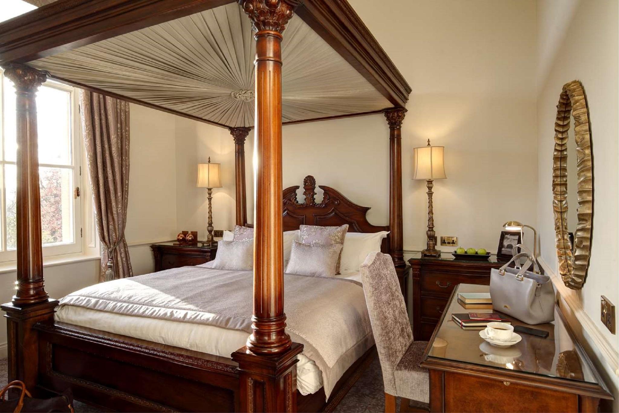 Macdonald Bath Spa Hotel Eksteriør bilde The photo shows a beautifully designed bedroom featuring a four-poster bed with a canopy. The bed is adorned with white linens and decorative pillows. On either side of the bed, there are bedside tables with lamps providing warm lighting. Large windo