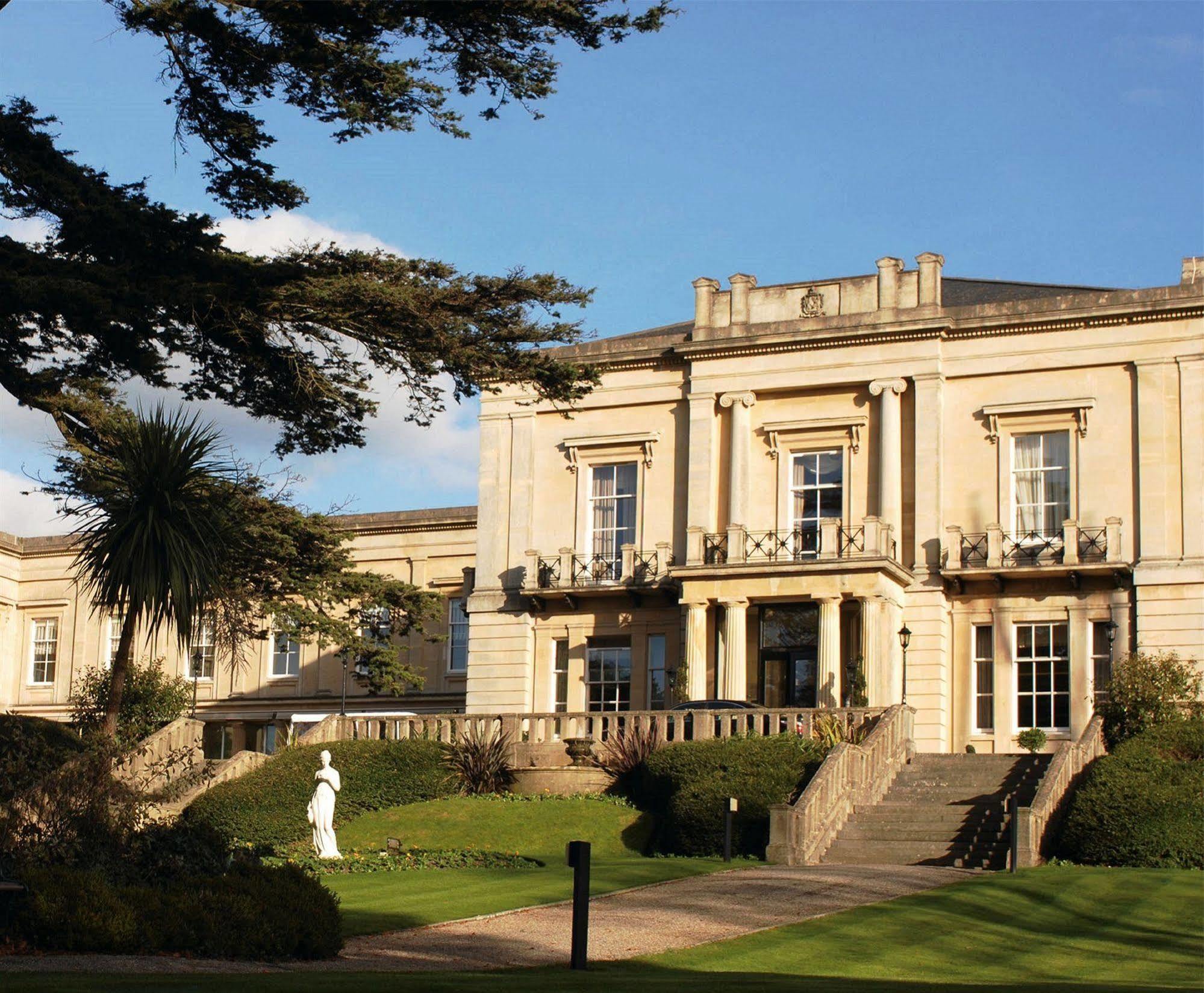 Macdonald Bath Spa Hotel Eksteriør bilde The photo shows an elegant building with classical architecture, featuring large windows and decorative elements. The facade is light-colored, and there are several balconies. In front of the building, there is a landscaped area with greenery, includ