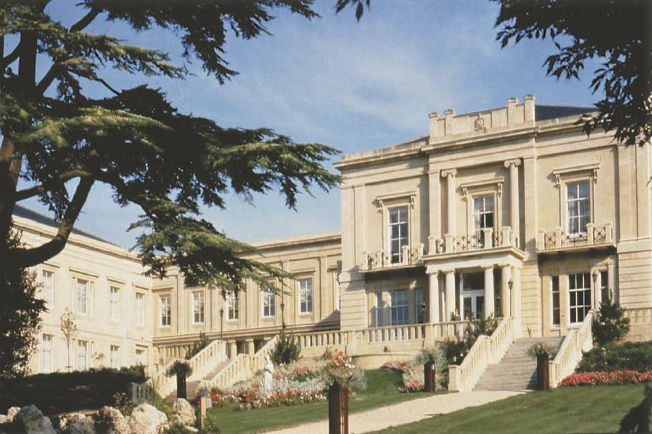 Macdonald Bath Spa Hotel Eksteriør bilde The photo depicts an elegant, stately building characterized by classical architecture. It features a symmetrical facade with large windows and decorative balconies. The structure is complemented by a lush green lawn and landscaped gardens, enhancing